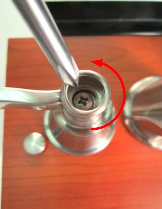 Once the handle cap is removed, the screw will be visible. Use a screwdriver to remove the screw by turning counter clockwise.
